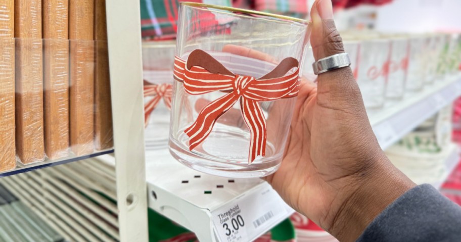 person grabbing glass tumbler with red ribbon in target store