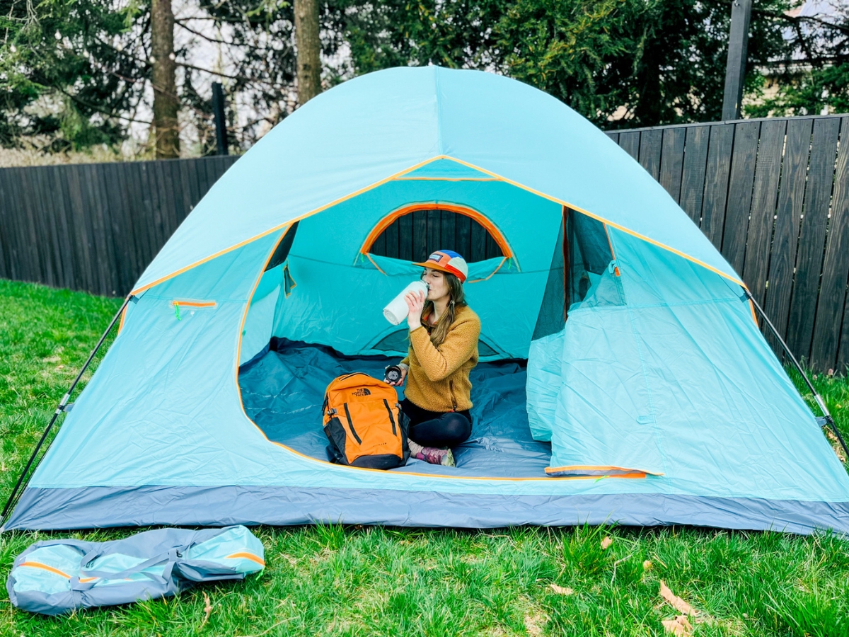 Woman sitting in a tent holding a water bottle