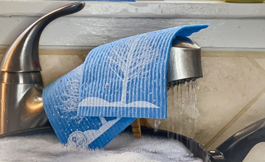 two blue swedish dishcloths on sink faucet