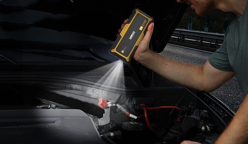 guy using car jump starter as flashlight