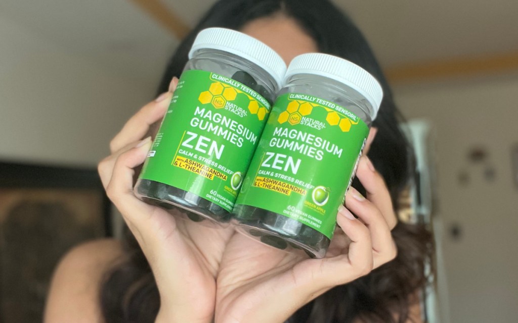 two bottles of magnesium gummies in front of womans face