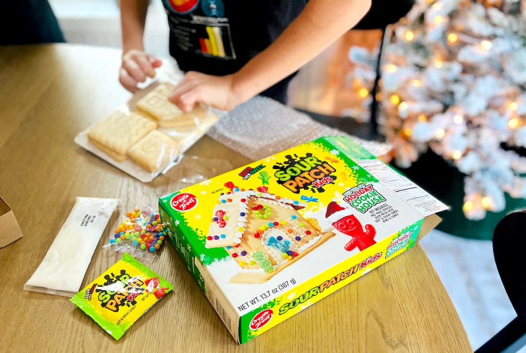 kid opening sour patch kids kit on table