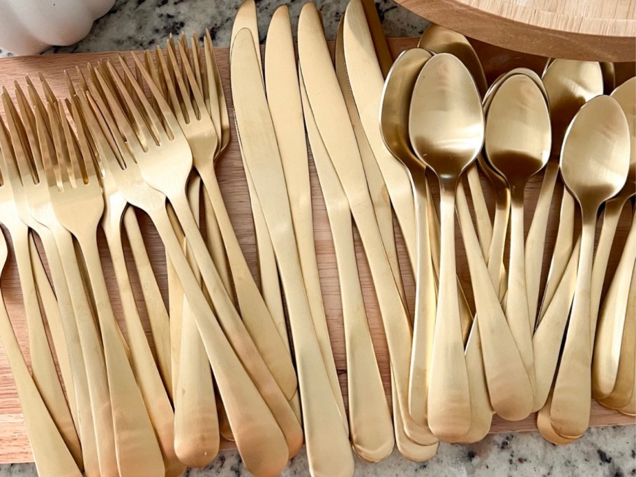 better homes & gardens matte gold flatware set on wooden board