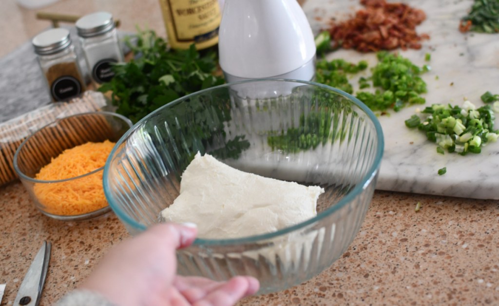 A bowl of cream cheese being used to make a bacon jalapeno cheese ball