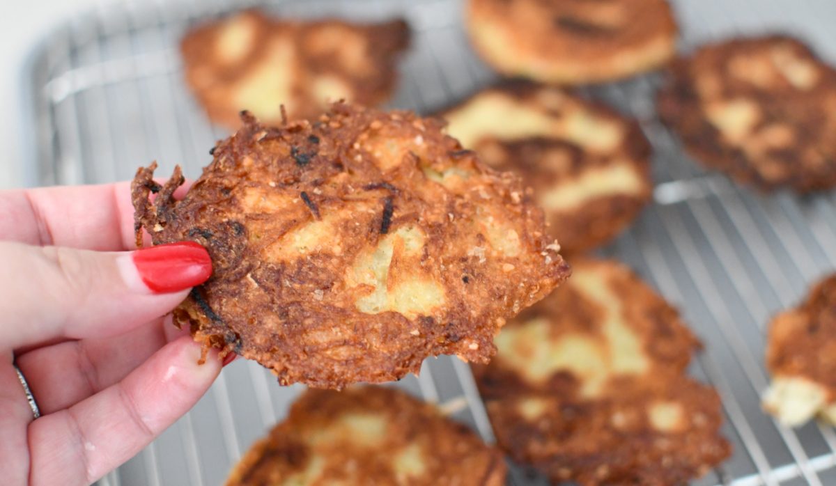 hand holding up a jewish potato latke that is crispy