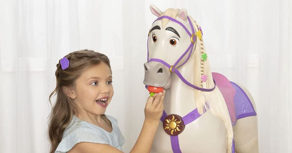 A little girl feeding a plastic apple to Maximus the horse