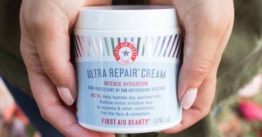 woman's hands holding a jar of First Aid Beauty Ultra Repair Cream