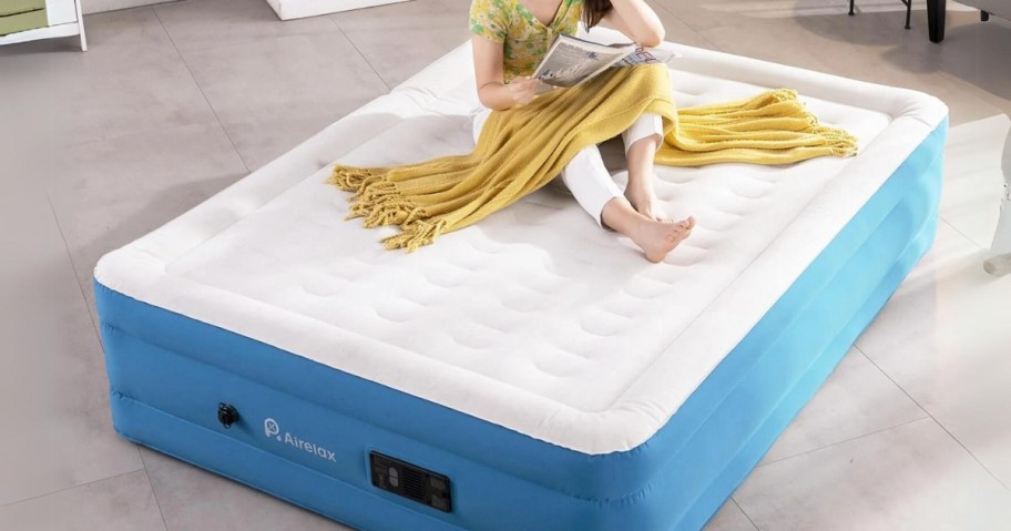 woman sitting on a white and blue large air mattress in a living room