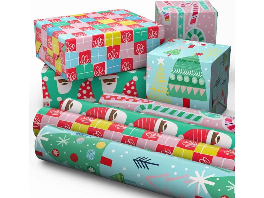 4 rolls of christmas wrapping paper in front of wrapped boxes