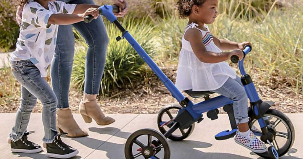 little girl riding a Yvolution Y Velo Flippa 3-in-1 Toddler Trike to Balance Bike while being pushed by mom and big brotehr