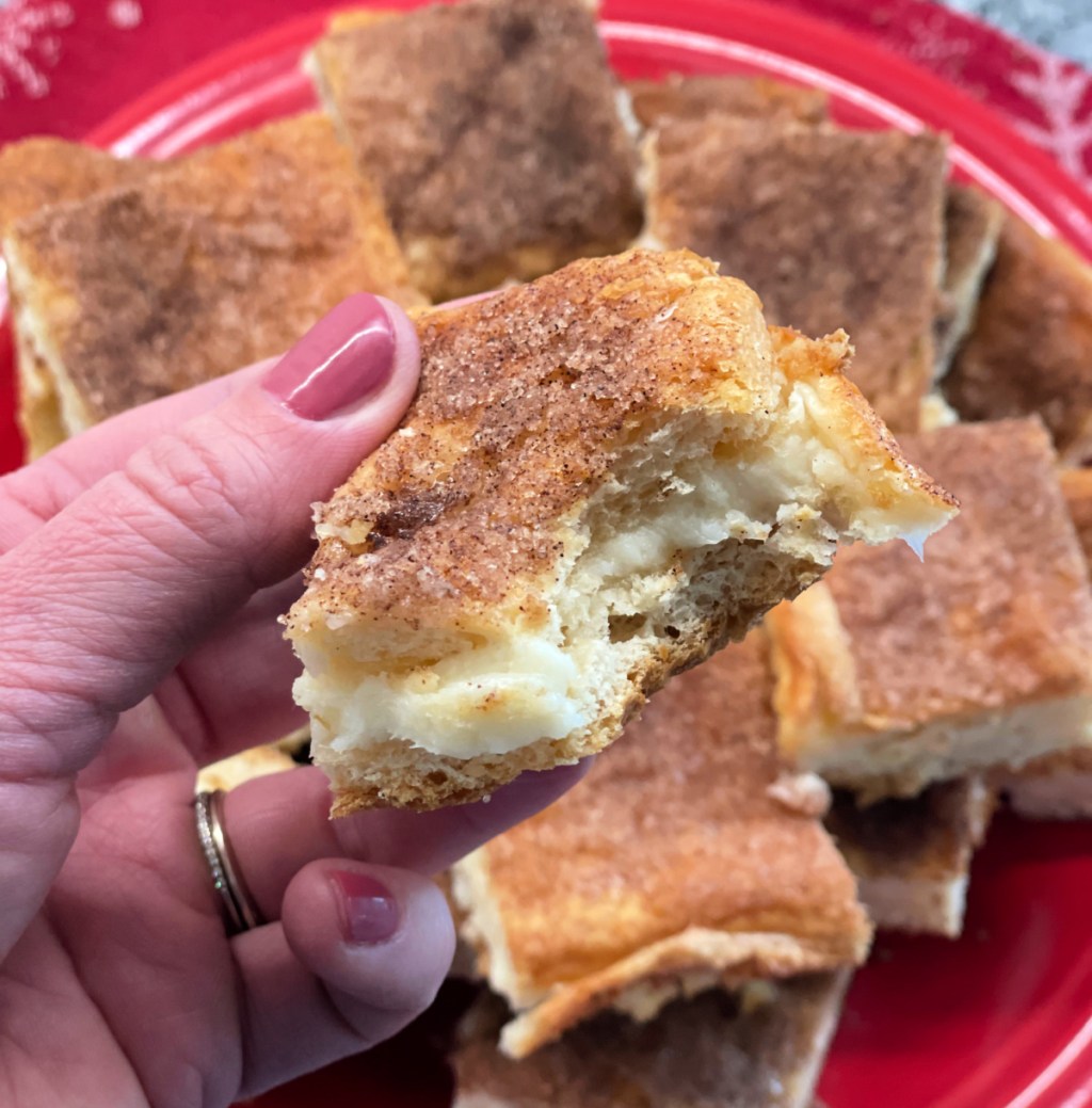 Hand holding up a half eaten sopapilla cheesecake bar 