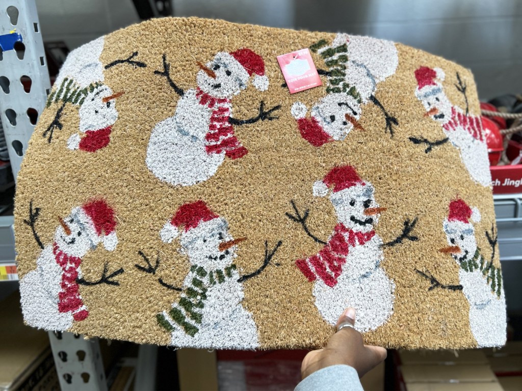 hand holding a snowman print doormat