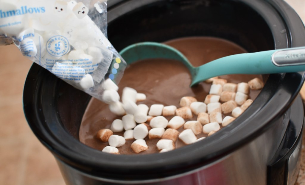 Dumping a bag of marshmallows into a Crockpot hot chocolate drink