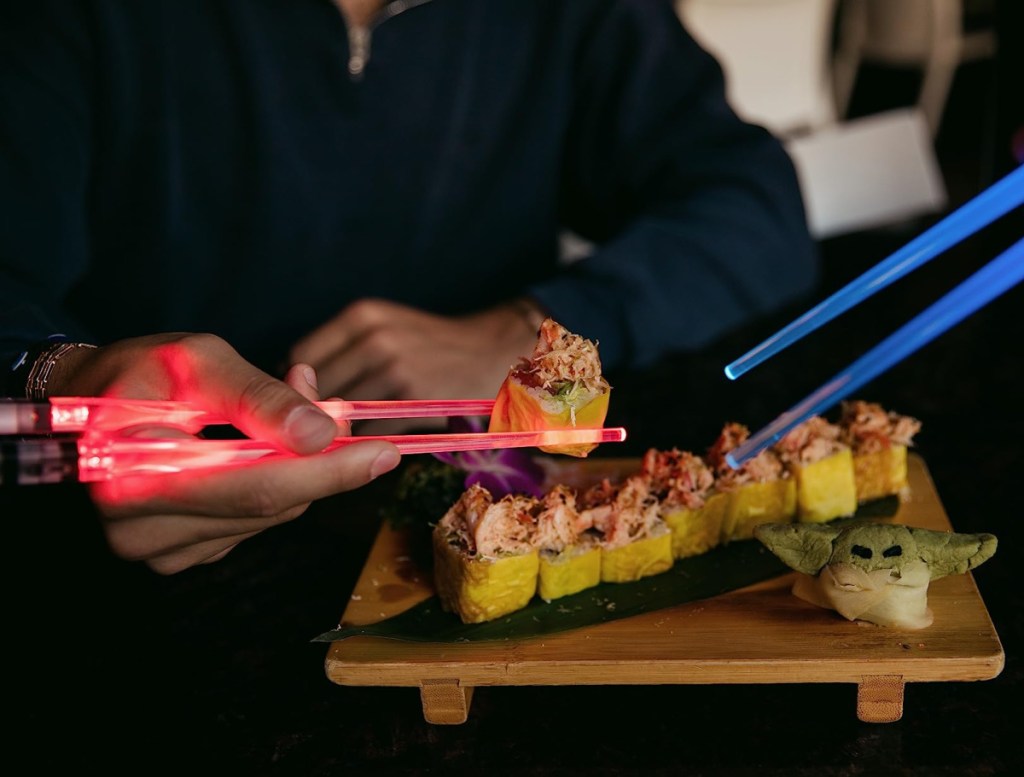 a customer using lightsaber chopsticks to eat sushi 