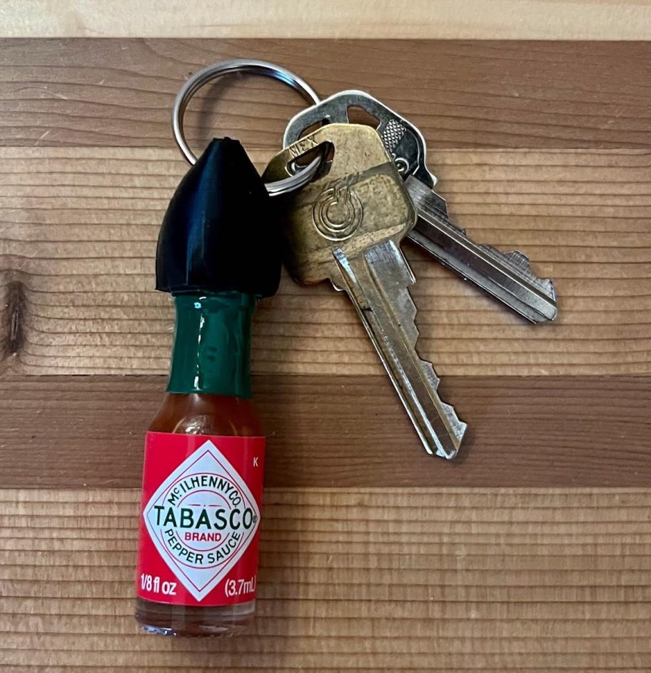 Mini Tabasco sauce keychain on keys laying on wood table