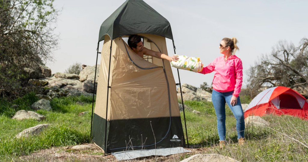 woman handing towel to man inside a shower tent