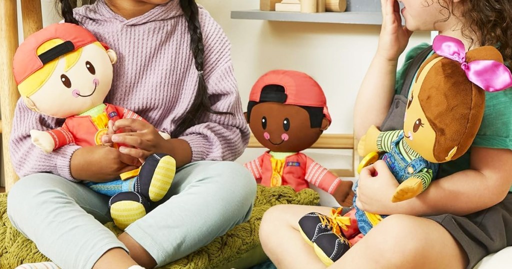 two girls sitting on floor holding plush dolls