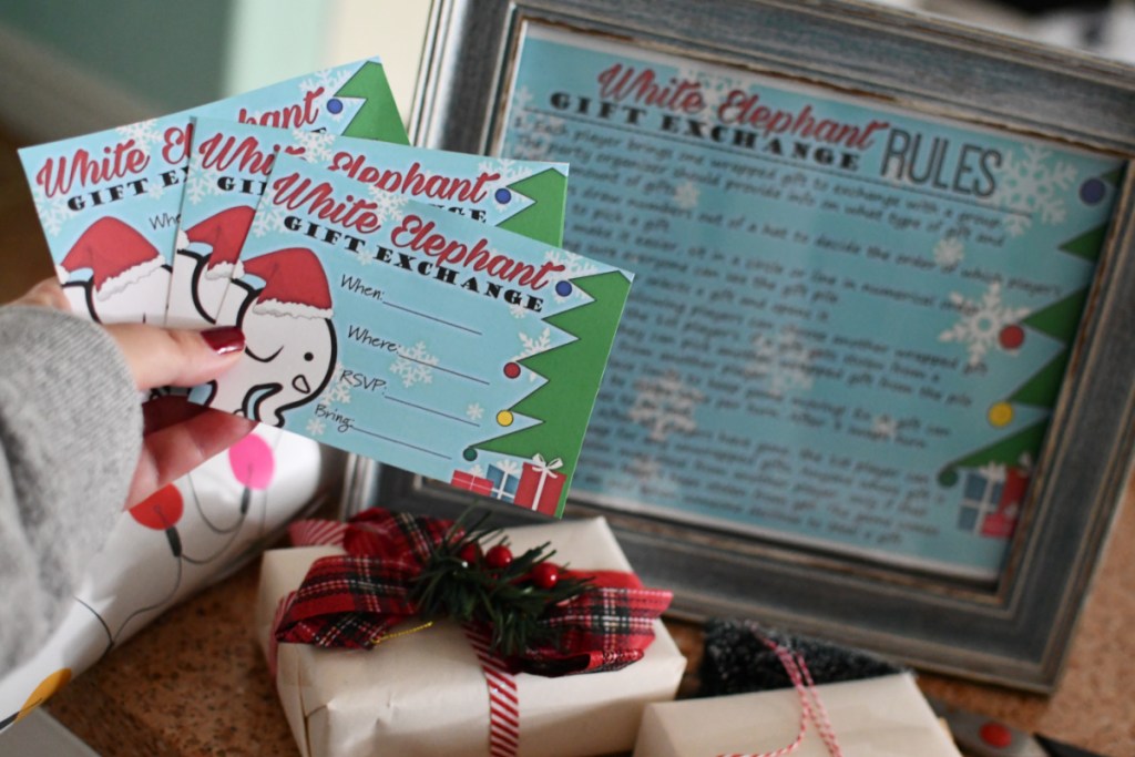 a hand holding white elephant invitations