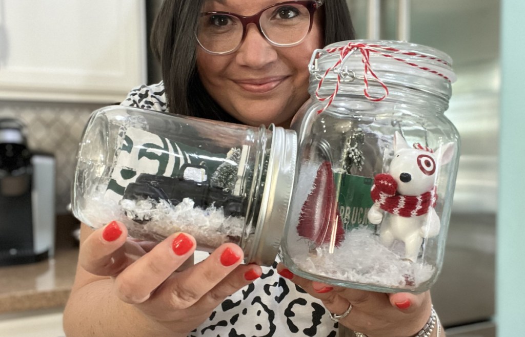 Woman holding up two mason jar diy snow globes.