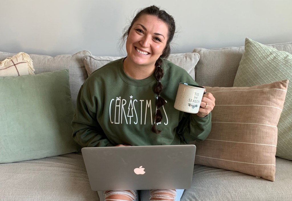 woman in christmas sweatshirt with onlineputer and coffee cup