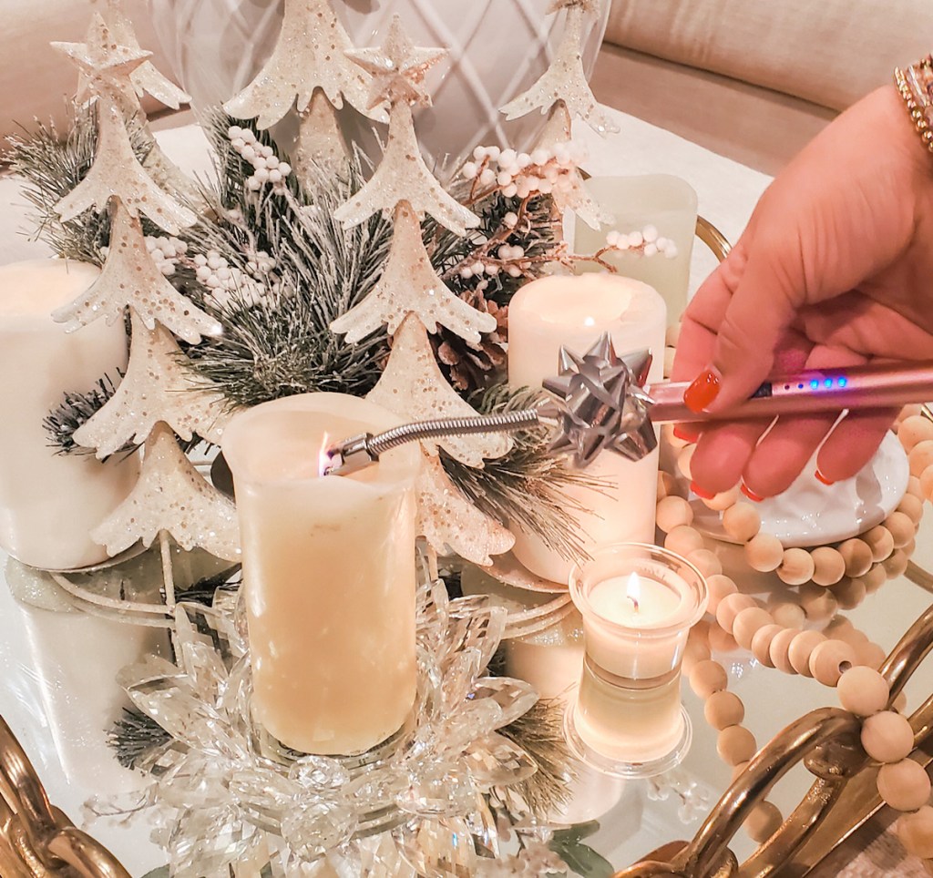 hand holding an electric lighter over candle