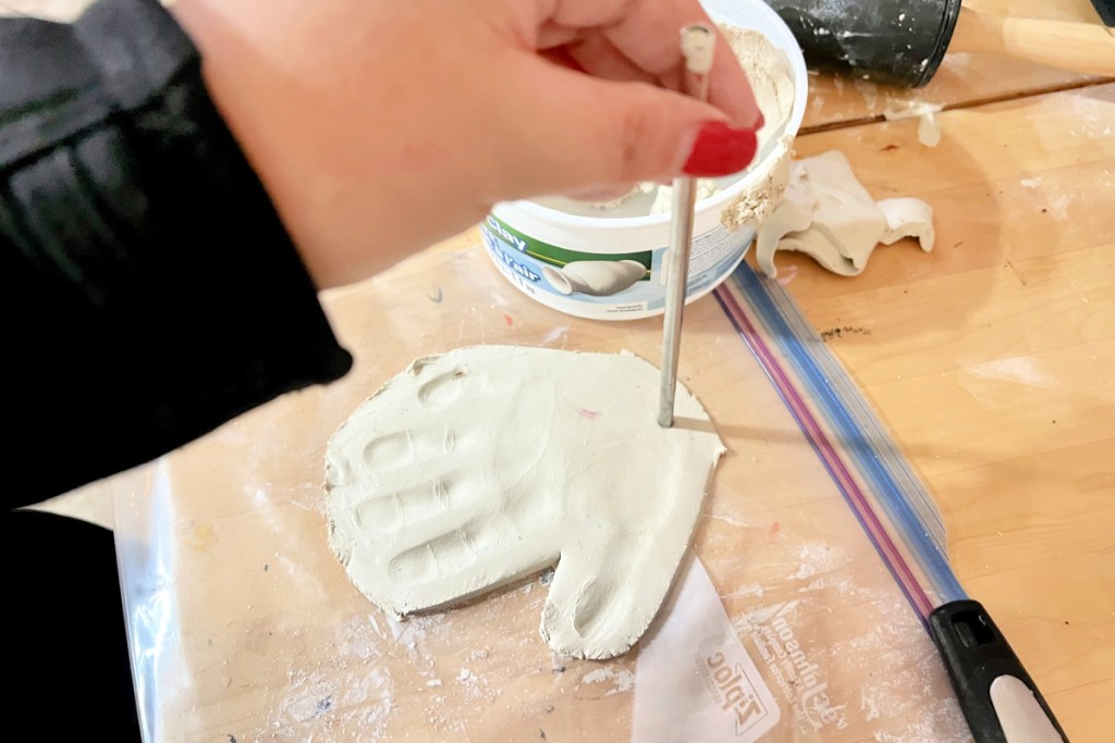 making a hole using a straw to hand ornament