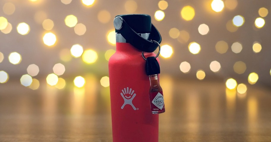 red hydro flask with mini tobasco sauce with blurry lights in background