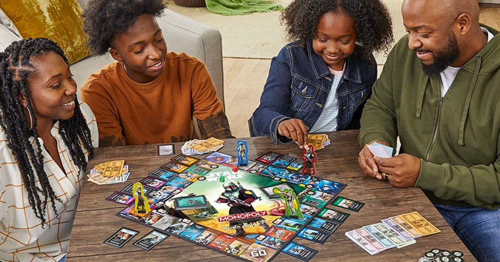 Son, daughter and parents playing star wars monopoly board game on coffee table