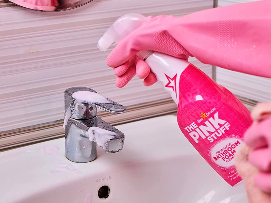 person wearing pink gloves spraying the pink stuff bathroom cleaner