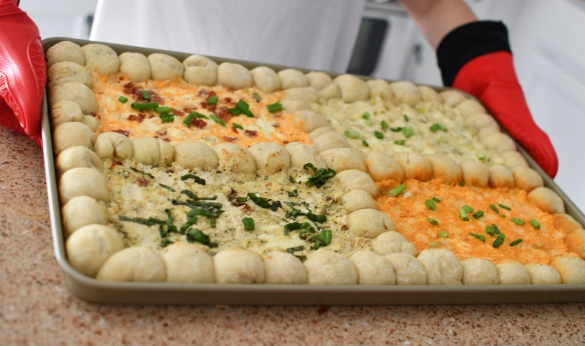 person holding an appetizer tray with four cheese dips on it