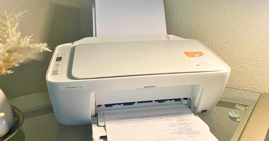 white HP printer on a desk with paper in both trays