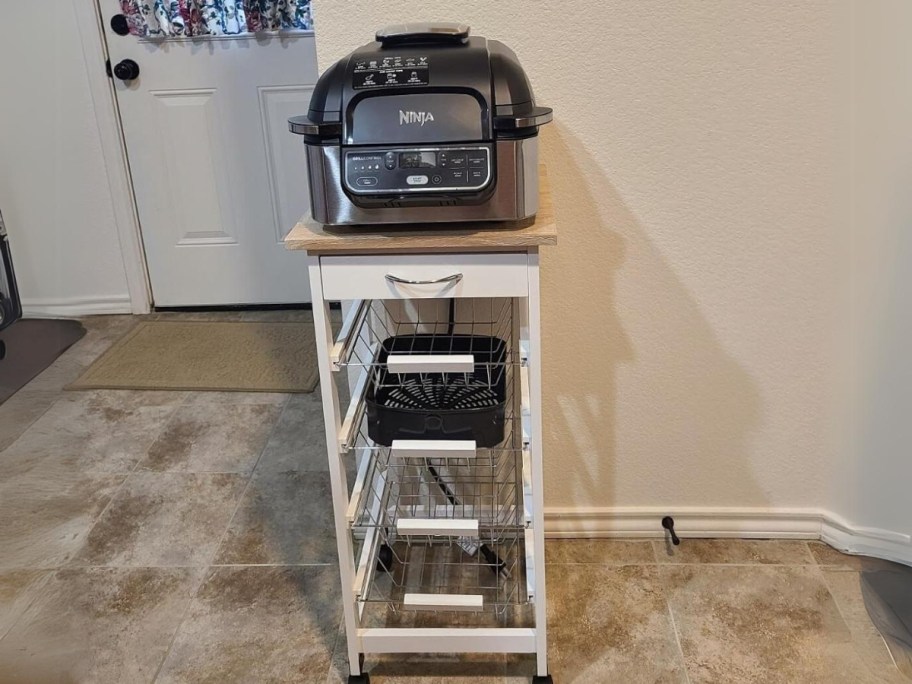 white small kitchen cart with 4 metal basket drawers with a Ninja Foodi on top in a kitchen