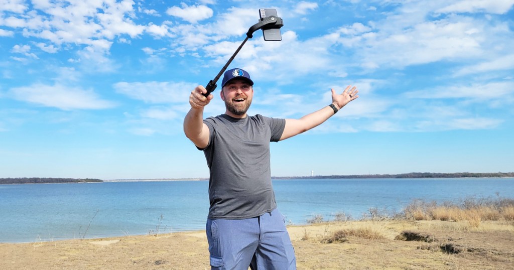 man on a beach using a selfie stick