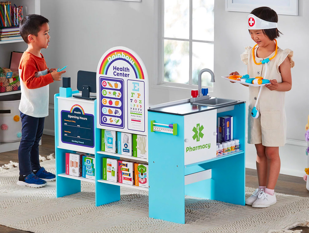 two kids playing with wooden health center playset