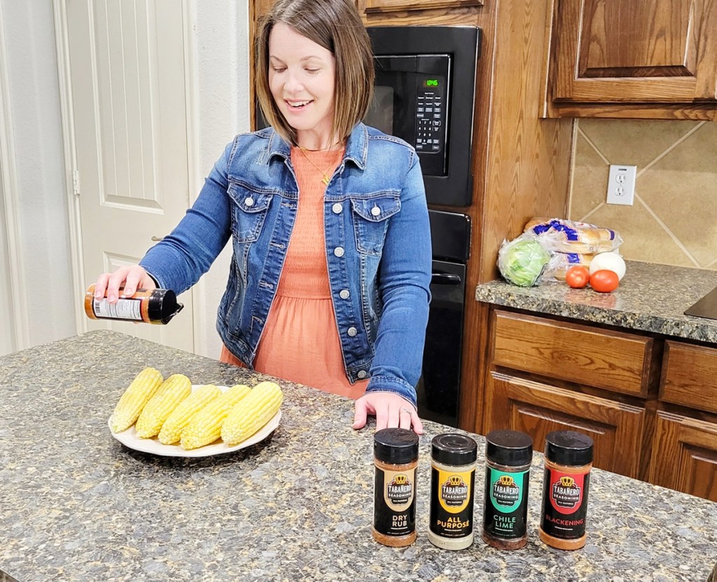 woman sprinkling seasoning on corn