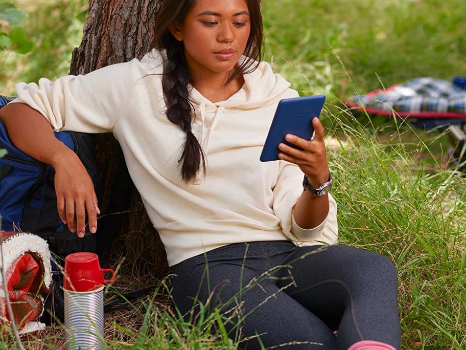 young woman reading on a Kindle outside