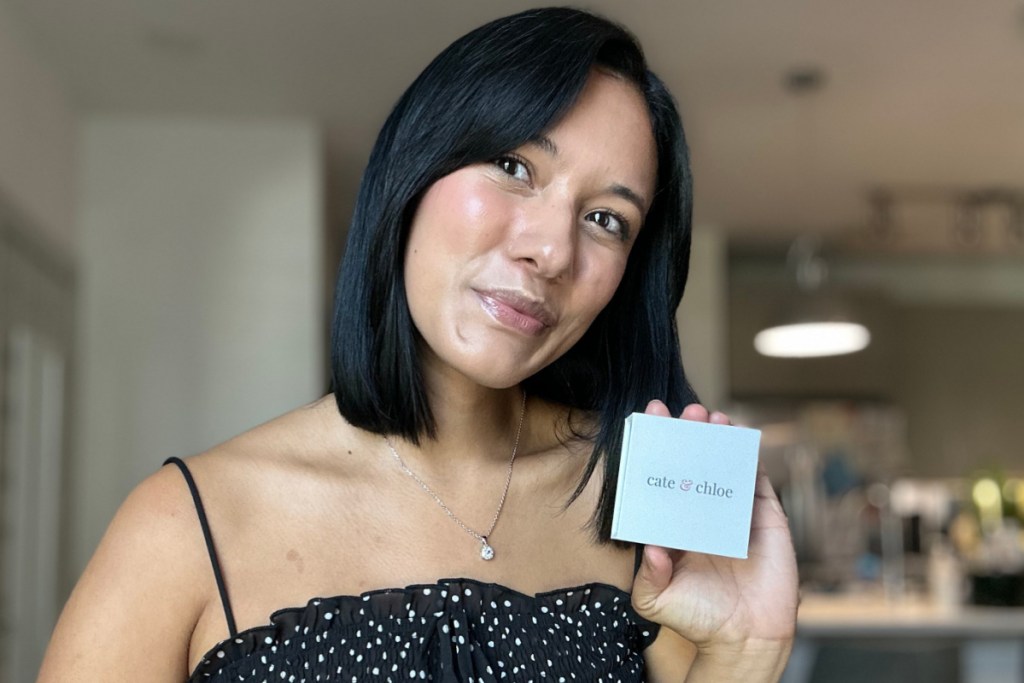 woman with short black hair wearing pendant neckalce and holding jewelry box