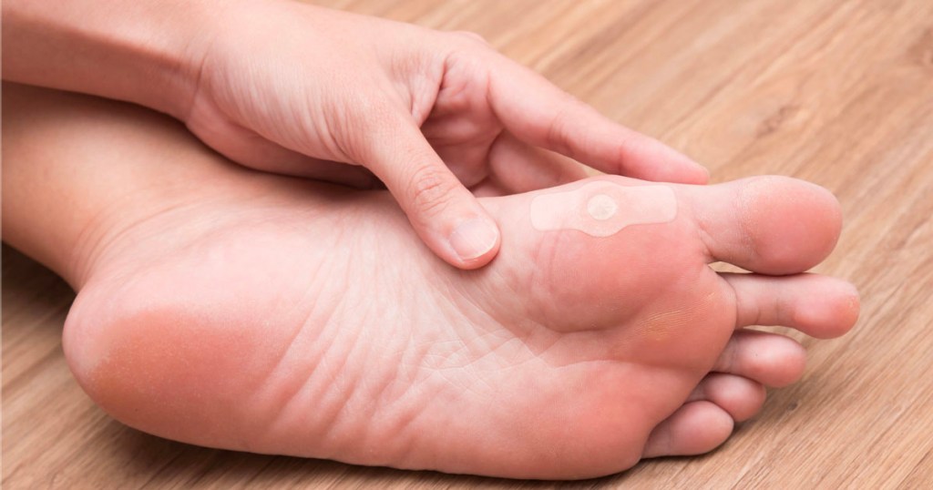 hand holding foot with corn cushion bandage on it