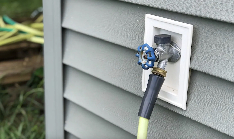 close up of hose bib on house siding