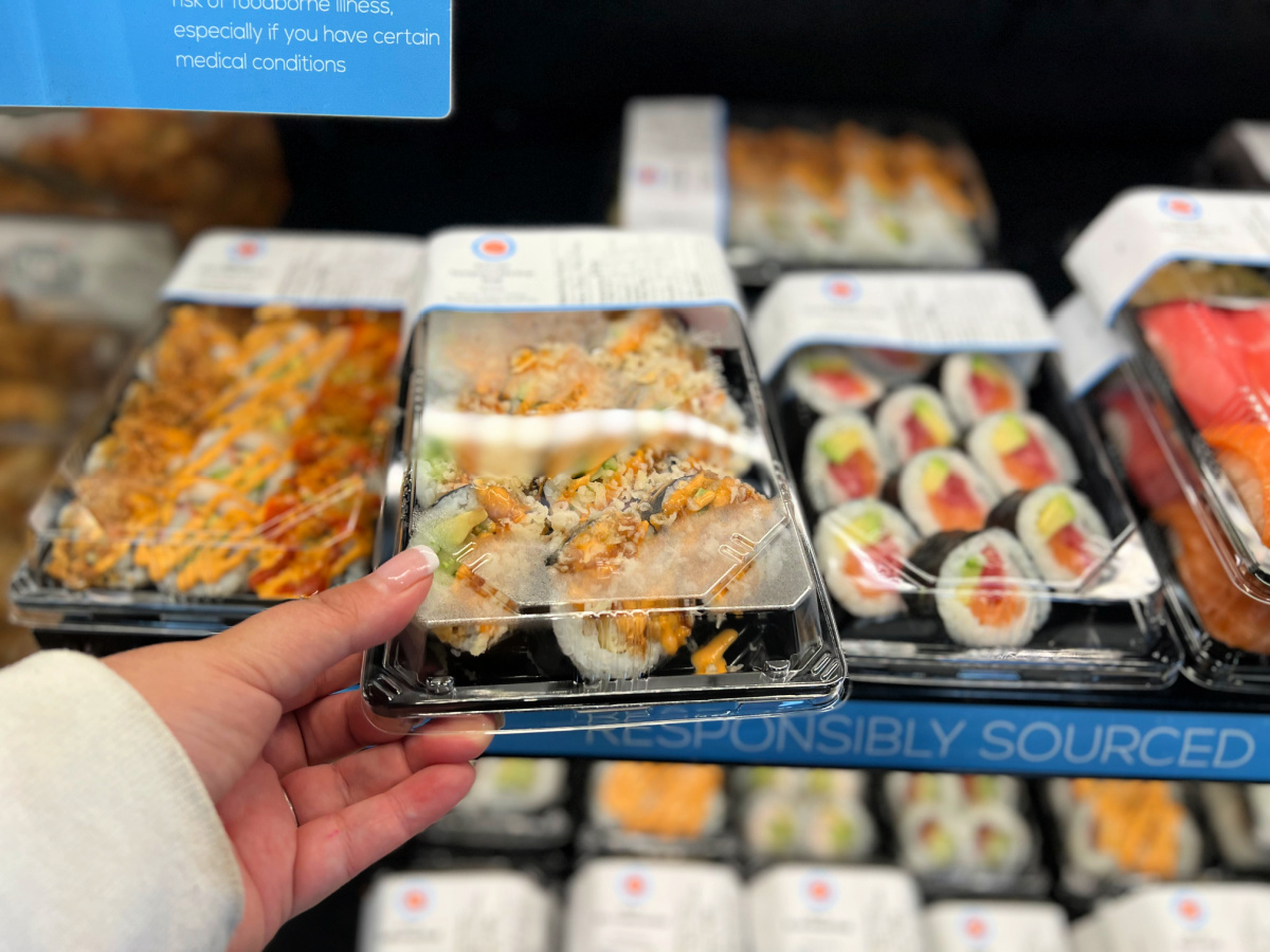 Woman holding grocery store sushi in-store. 