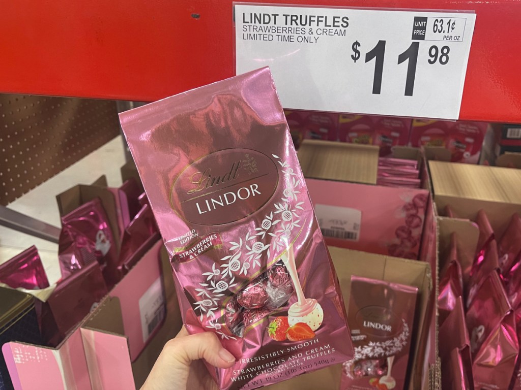 hand holding Lindt Strawberries and Cream White Chocolate Truffles 19oz Bag at the store