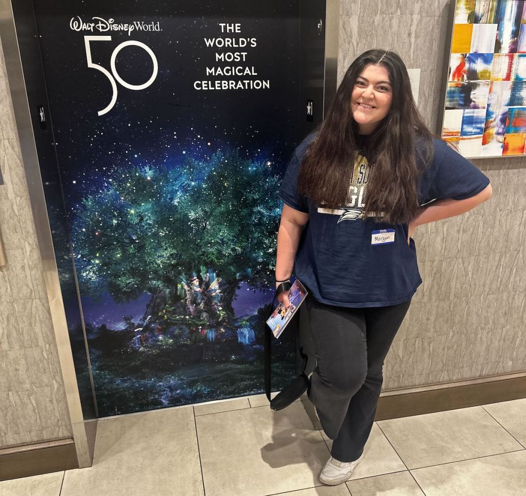 girl standing next to walt disney world sign 