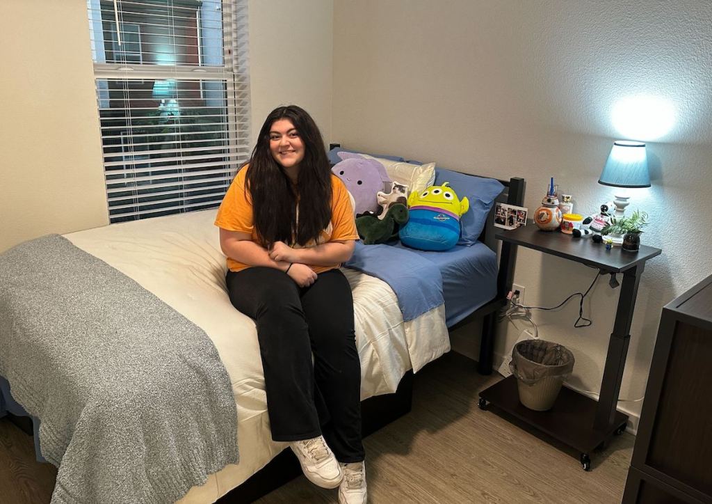 girl sitting in dorm room on bed 