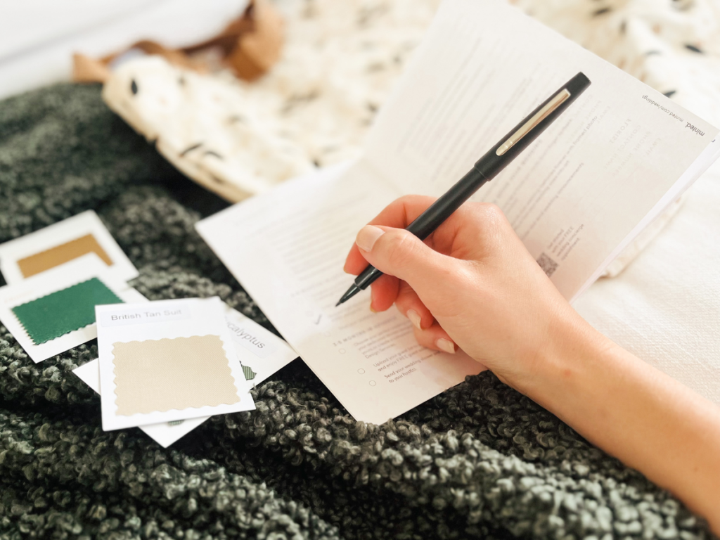 Minted Wedding Planning Journal shown with woman's hand writing in it