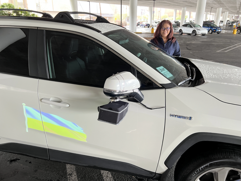 Woman standing next to her car with an Adway car advertisement displayed on the side