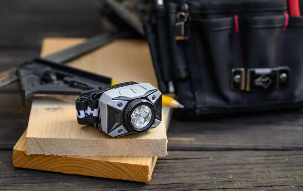 Headlamp sitting on two pieces of wood next to a toolbag.