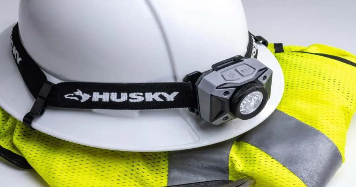 Head Lamp on a construction hard hat laying on a yellow construction vest.