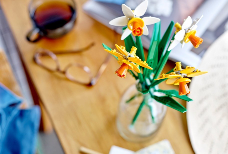 glass vase filled with LEGO Botanicals Collection Daffodils on a desk near the window