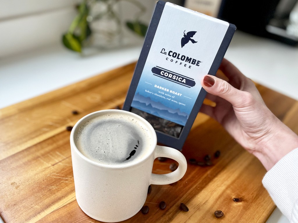 holding box of La Colombe Coffee near mug of coffee