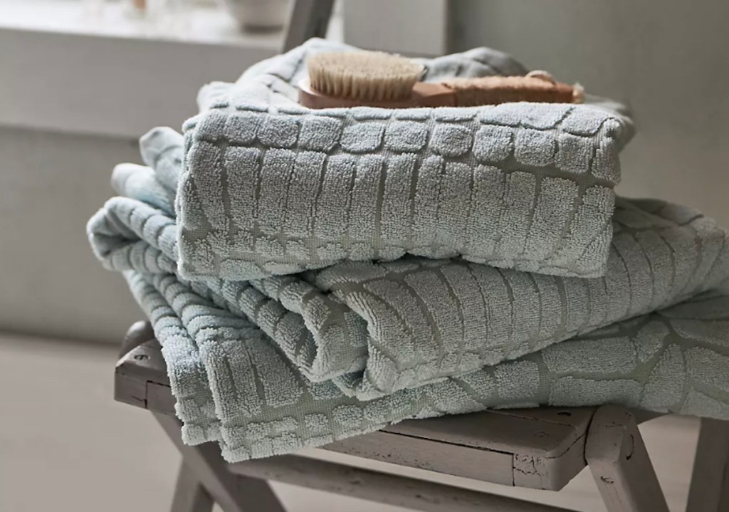 Stock photo of mint green bath towels and wooden brush on wood chair in bathroom